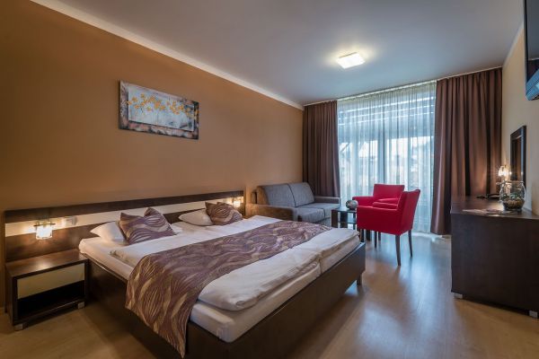Interiér apartmánu s manželskou postelí a sedacím koutem